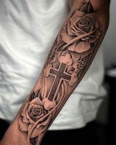 a man with a cross and roses tattoo on his arm in black and grey colors