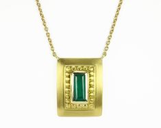 Displayed in a one of kind, green gold, Colombian emerald hand-made necklace. A divine 1.60-carat elongated emerald sits in a secure bezel setting. The alluring centerpiece displays a rich blue-green color, true to its prized origin; Muzo, Colombia. Beautiful clarity is seen in this gem as it is eye clean, small imperfections are natural, adding ambiance and character to the stone. A golden halo rises around the gemstone, providing texture and depth. A hand brushed satin finish is dexterously ap Formal Hallmarked Emerald Necklace, Traditional Emerald Necklace For Anniversary, Yellow Gold Necklace With Emerald Rectangular Pendant, Rectangular Emerald Jewelry With Bezel Setting, Yellow Gold Gemstone Necklaces For Ceremonial Events, Traditional Emerald Necklaces For Anniversary, Emerald Necklace With 17 Jewels For Celebration, Formal Emerald Rectangular Pendant Necklace, Fine Jewelry Emerald Necklace In Gold