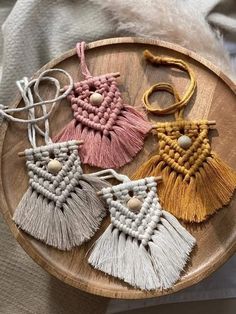 four tasseled earrings on a wooden tray with white and pink beads, one in the shape of a heart