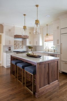 a kitchen island with stools in front of it and lights hanging from the ceiling