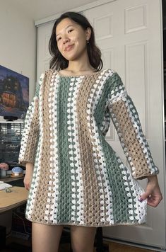 a woman standing in front of a door wearing a crocheted dress with long sleeves