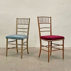 two chairs sitting next to each other in front of a white wall with red and blue upholstered cushions