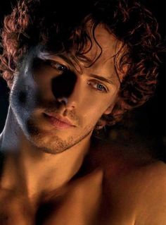 a shirtless man with curly hair and blue eyes