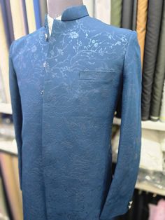 Make a statement with this elegant and stylish Indo-Western Sherwani. Crafted with meticulous attention to detail, this Sherwani is a perfect blend of traditional Indian and contemporary Western influences. The deep blue color of the Sherwani is both sophisticated and timeless. It is adorned with a subtle yet stunning floral pattern that adds a touch of sophistication and charm. The pattern is woven into the fabric, giving the Sherwani a rich and textured look.  The Sherwani features a classic m Traditional Drape Wedding Suits With Dabka, Wedding Suits With Dabka And Traditional Drape, Dabka Embellished Wedding Suits With Traditional Drape, Unstitched Zari Work Suits For Reception, Blue Sherwani For Wedding, Blue Formal Unstitched Suit With Traditional Drape, Fitted Sherwani With Pallu For Ceremony, Unstitched Blue Wedding Suits, Elegant Unstitched Dabka Suit For Wedding