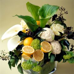 a vase filled with lots of different types of flowers and fruit on top of a table