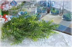 a table topped with glasses filled with water and greenery