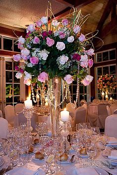 a tall vase filled with pink and white flowers sitting on top of a dining room table