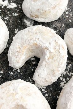 doughnuts with powdered sugar on them sitting on a black counter top, ready to be eaten