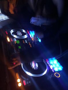 the dj is mixing music on his turntable in the dark with bright lights coming from behind him