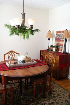 a dining room table with christmas decorations on it and lights hanging from the ceiling above