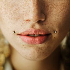 a woman with freckles and piercings on her nose