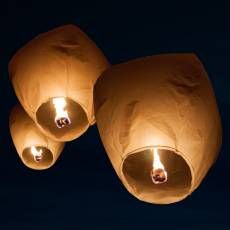 three paper lanterns lit up in the night sky with one light turned on and two glowing