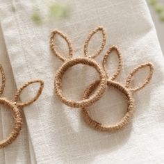 two napkin rings are sitting on top of a white table cloth with flowers in the background