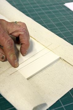 an older person is cutting fabric on a piece of white paper with scissors and tape