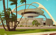 an old photo of a building with palm trees in the foreground and a blue sky background