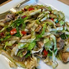 a white plate topped with lettuce and meat next to a knife and fork