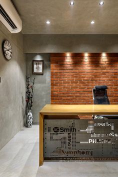 an office with a brick wall and wooden desk in front of the reception area is lit by recessed lights