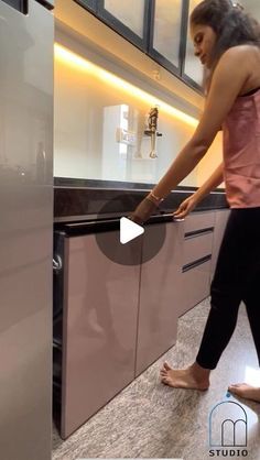 a woman standing in front of a kitchen counter top next to a refrigerator freezer