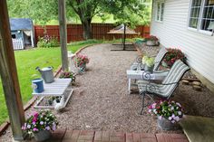 an outdoor patio with chairs and potted plants on the side of the house,