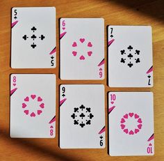 four playing cards are arranged in the shape of hearts and cross symbols on a wooden table