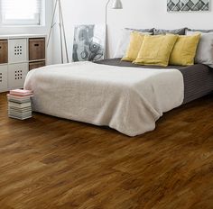 a bedroom with wood floors and white walls, including a bed that has yellow pillows on it