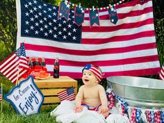 a baby sitting on the grass in front of an american flag banner and other decorations