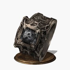 an intricately designed ring with a skull in the center on a wooden stand against a white background