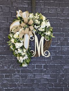 a wreath with the letter m hanging on a brick wall