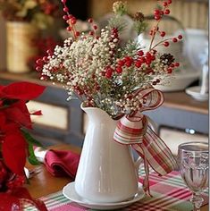 a white pitcher filled with flowers on top of a table next to plates and utensils