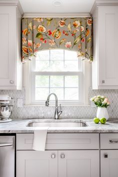 a kitchen window with flowers on the valance, and a sink in front of it