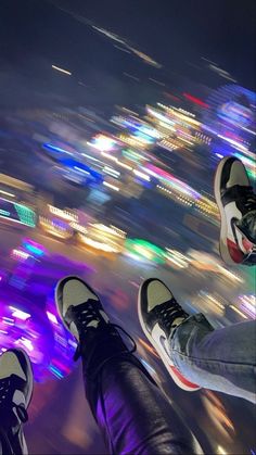 two people standing on top of a building with their feet up in the air at night