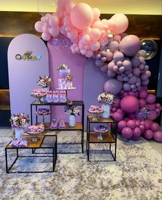 balloons and cake are on display in front of a wall with purple, pink and white decorations