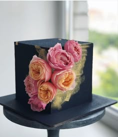 there is a black cake with pink flowers on it