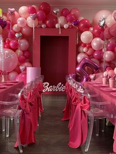 a room filled with lots of pink and white balloons on the walls, tables and chairs