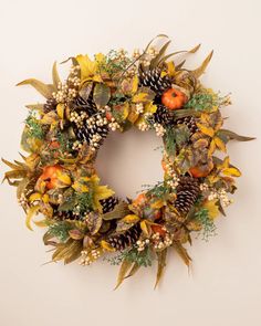 a wreath with pine cones, oranges and other autumn foliage is hanging on the wall