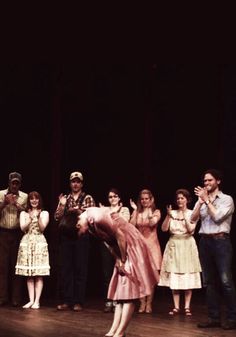 a group of people standing on top of a wooden floor in front of a stage