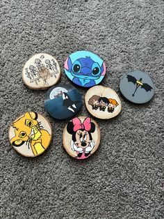 six disney pinbacks are laying on the carpet