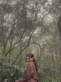 a woman walking in the woods on a foggy day