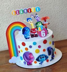 there is a birthday cake that has the characters on it and rainbow in the background