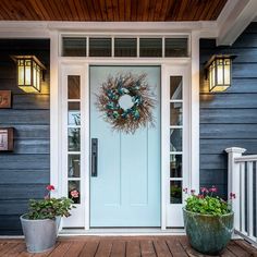 a blue front door with two planters and a wreath hanging on it's side