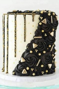 a black and white cake with gold decorations on it's side, sitting on a plate