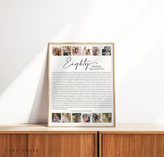 a framed poster on top of a wooden cabinet next to a white wall with the words happily written in cursive writing