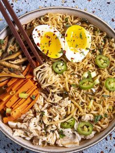 a bowl filled with noodles, carrots and an egg on top of it next to chopsticks