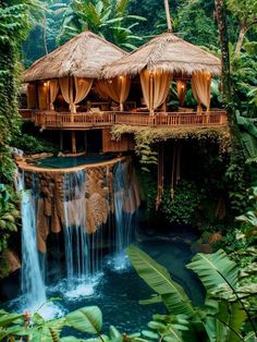 an outdoor restaurant with waterfall and tiki huts on the roof, surrounded by greenery