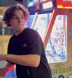 a young man holding a red frisbee in front of a vending machine