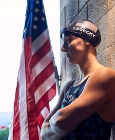 a man standing next to a brick wall with an american flag in front of him