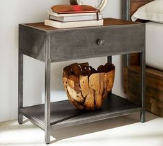 a wooden basket sitting on top of a metal shelf next to a bed and nightstand