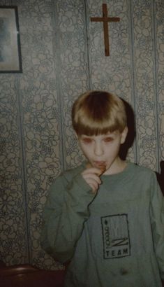 a young boy brushing his teeth in front of a wall