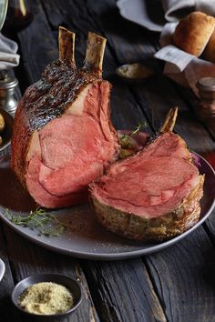 a piece of roast beef on a plate with garlic bread and mustard in the background