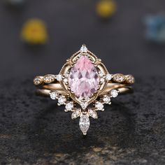 a close up of a ring with a pink stone in the center and white diamonds around it